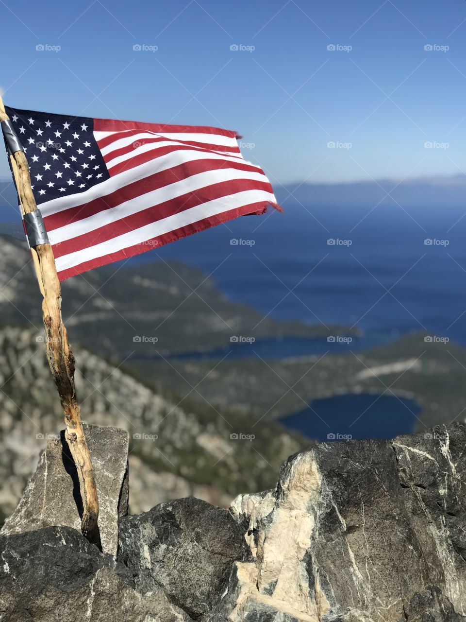 The American flag proudly waving over the majestic blue Lake Tahoe. 