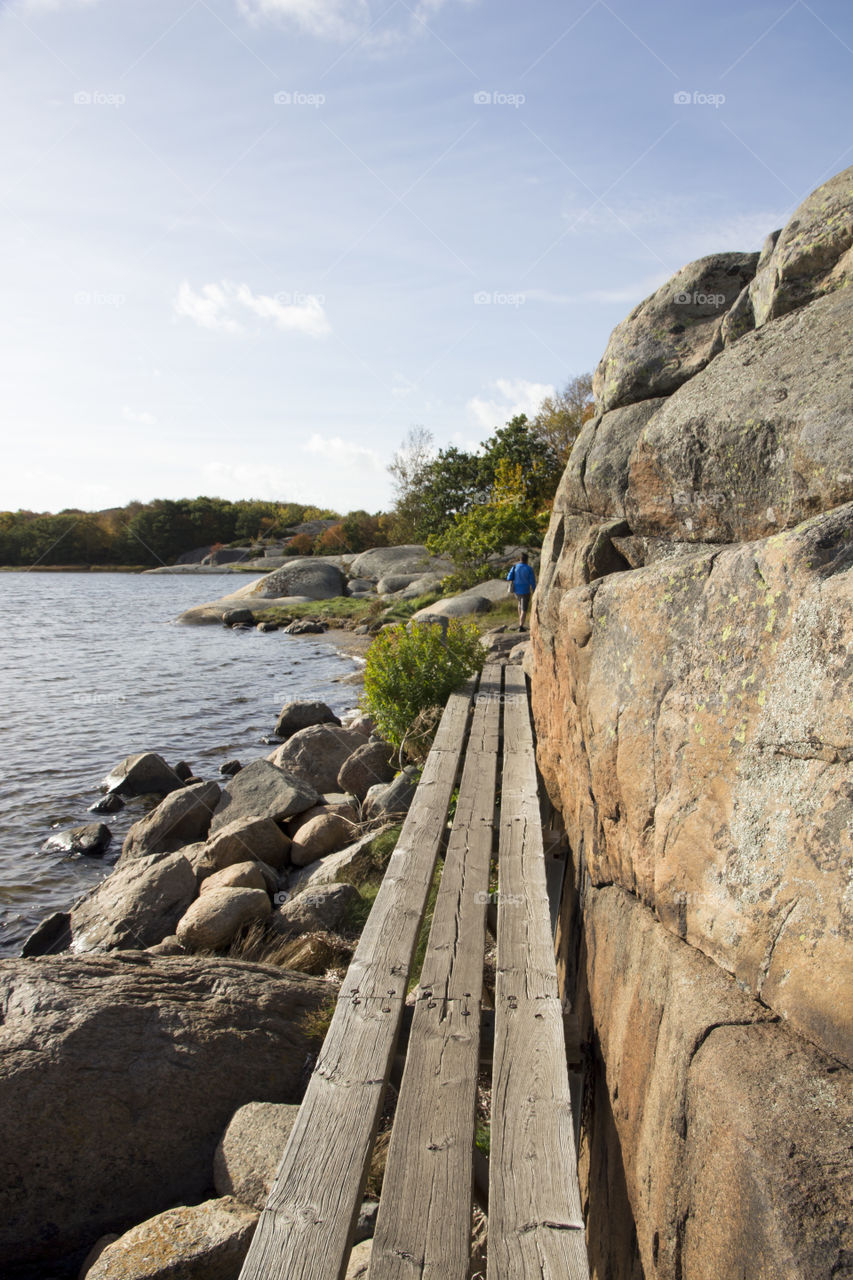 Man hiking on wood trail by the sea 