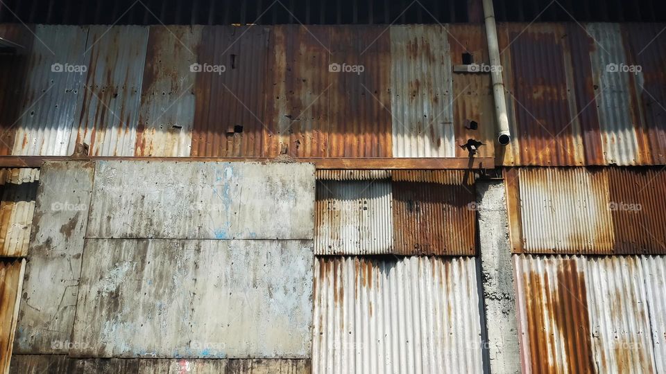 Old building covered with rusty corrugated tin walls and rolling door.