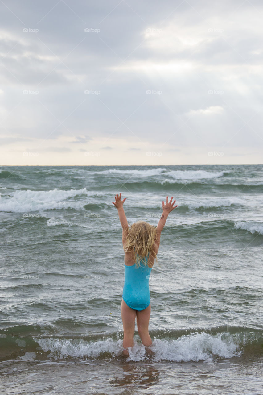 Girl playing at the beach of Tylösand outside Halmstad in Sweden. It's about to get stormy weather but the girl is having fun swimming and playing in the water.