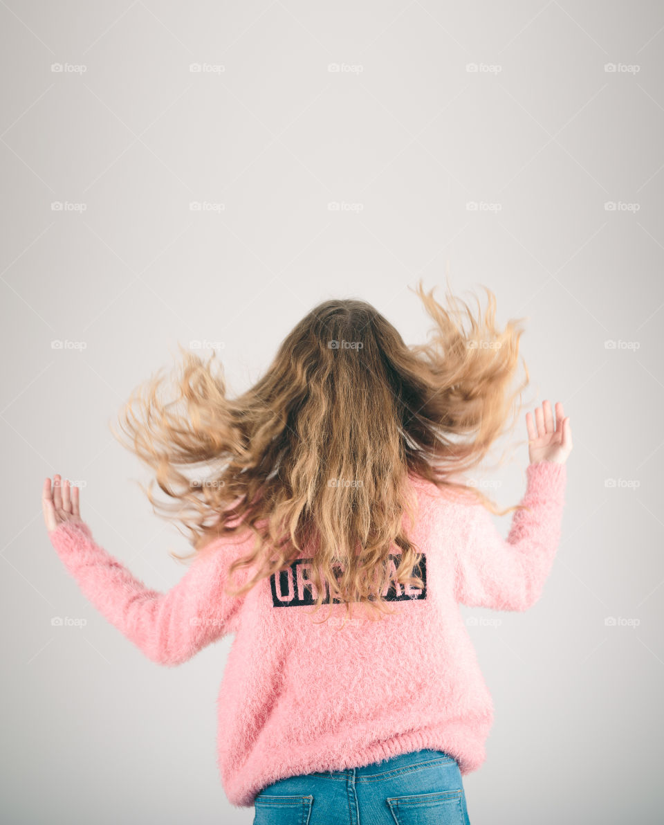 Back view of girl jumping in the air over plain background