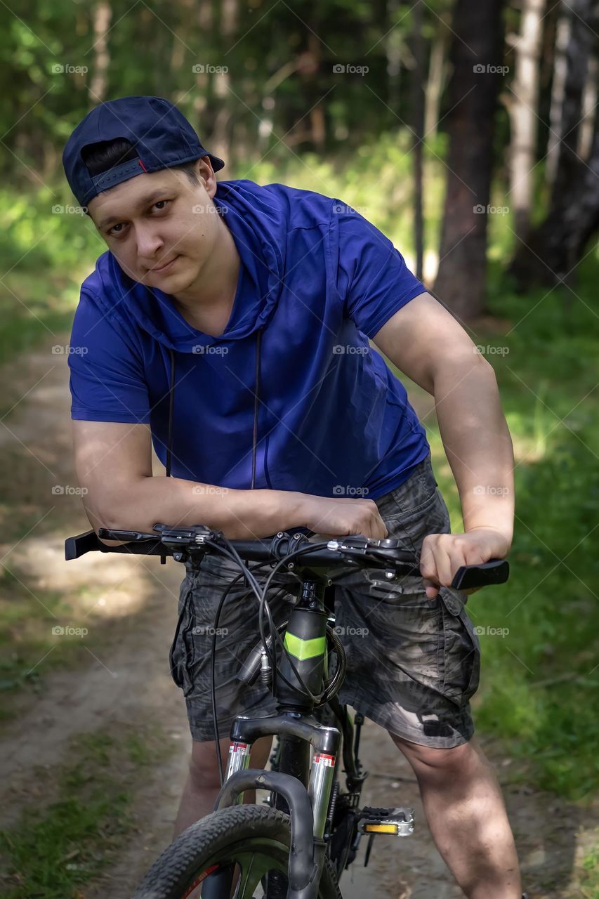 Close-up portrait of a young man in the park on a bicycle summer season sports