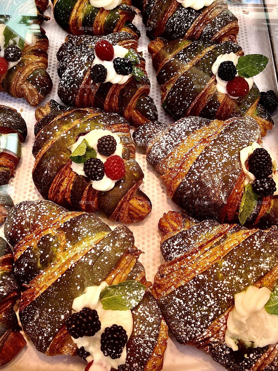 The photo shows delicious croissants generously decorated with fresh berries. The golden, flaky crust of the croissants contrasts with the vibrant colors of raspberries, blueberries and blackberries.
