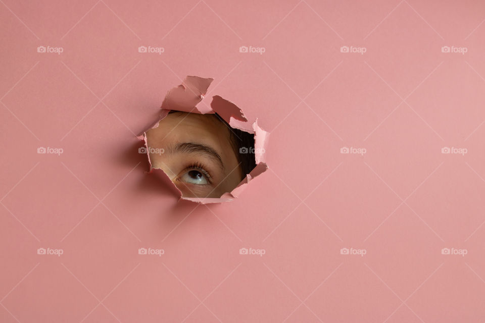 Abstract image with child looking up through the hole in the pink paper. Copy space.