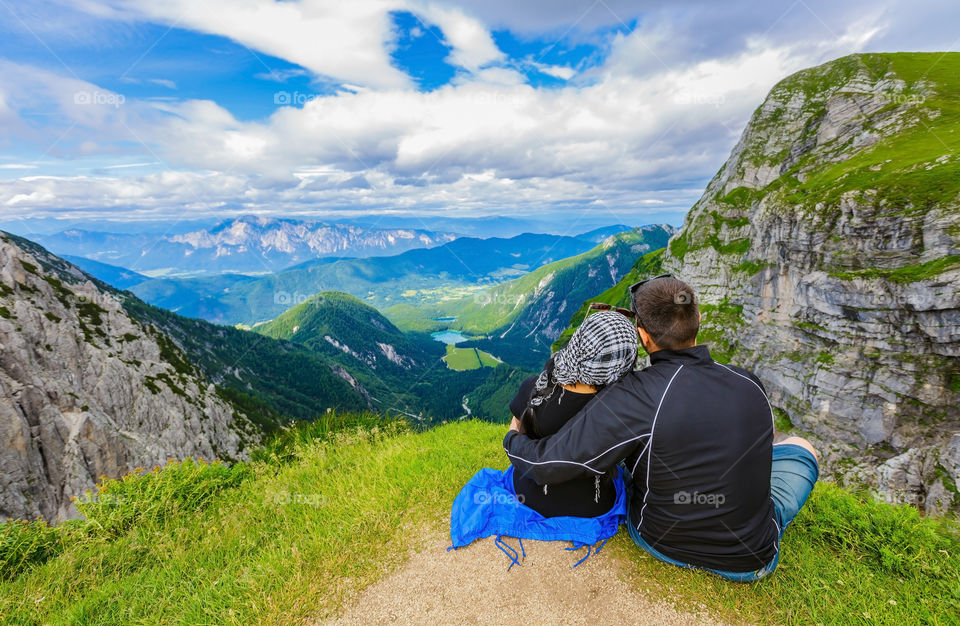 Couple sitting on top of mountain overlooking the view