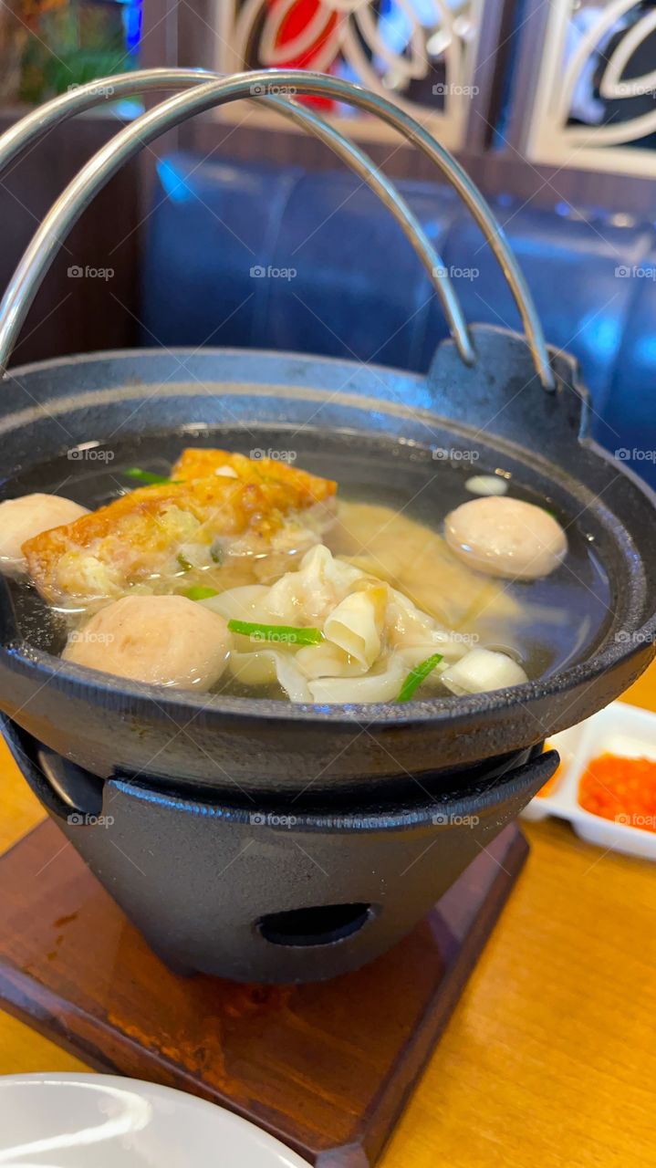 Steamboat soup with meat balls and fish cake,put on the traditional stove on the table, ready for served