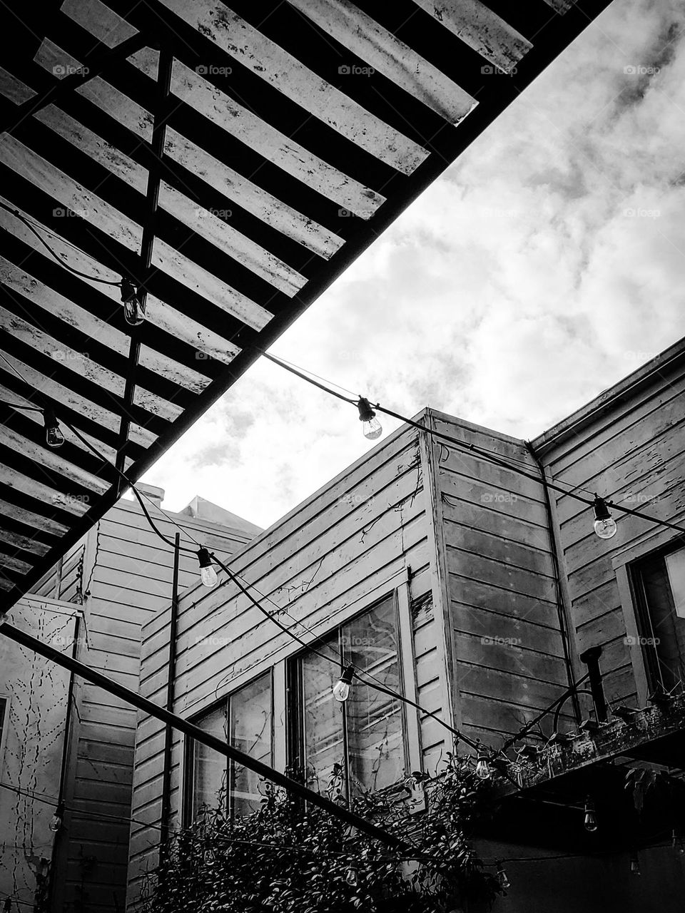 Looking up through the backyard of a patio in San Francisco California in black and white with stormy skies and wooded buildings 