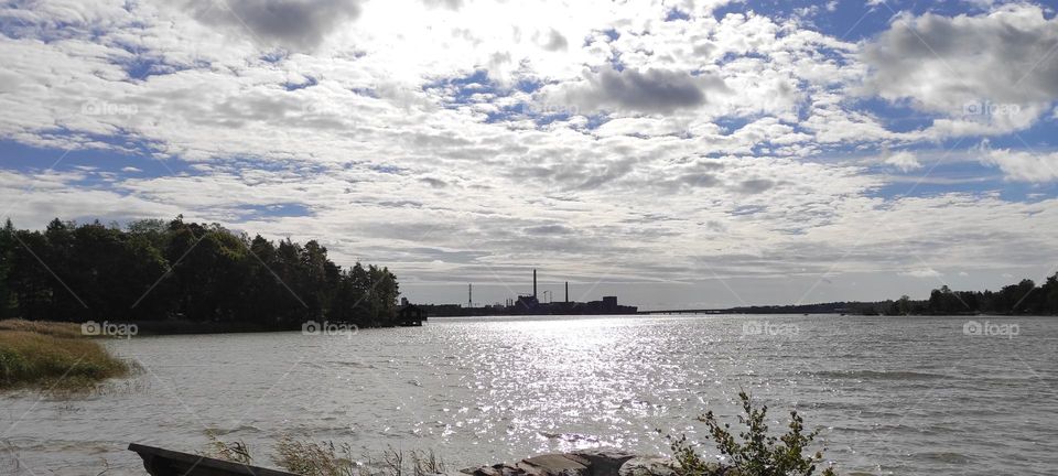 Far distance view at the industry zone in Helsinki with a beautiful lake and a cloudy blue sky