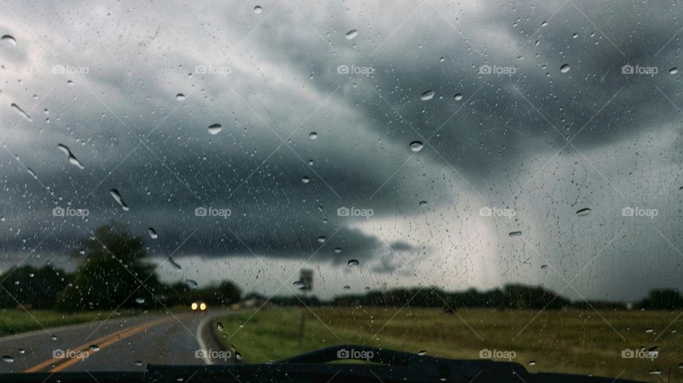 Driving thru a storm with heavy rain clouds up ahead and car light coming towards us