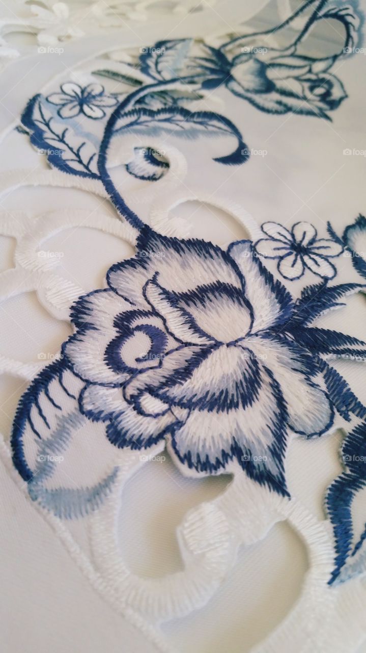 Blue flower embroidered upon table cloth.