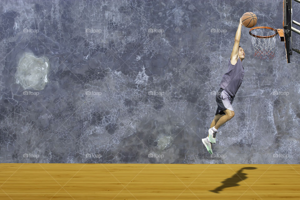 Basketball in hand man jumping Throw a basketball hoop On the wooden floor Background plaster wall loft  with The pattern of cracks.