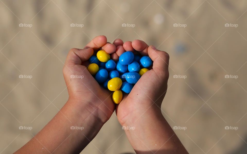 beautiful colored sweets, yellow and blue in the hands of a child, folded in the form of a heart