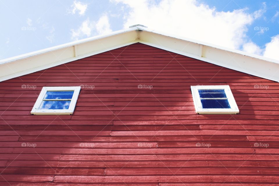 A huge barn with a window reflecting a perfect summer sky