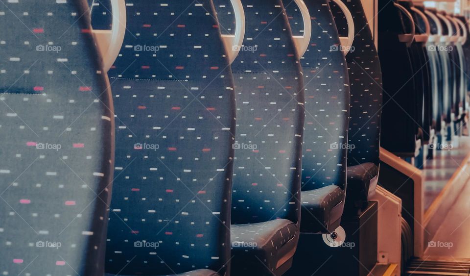 Soft textile blue chairs inside a European train rhythmically diagonally, close-up side view.