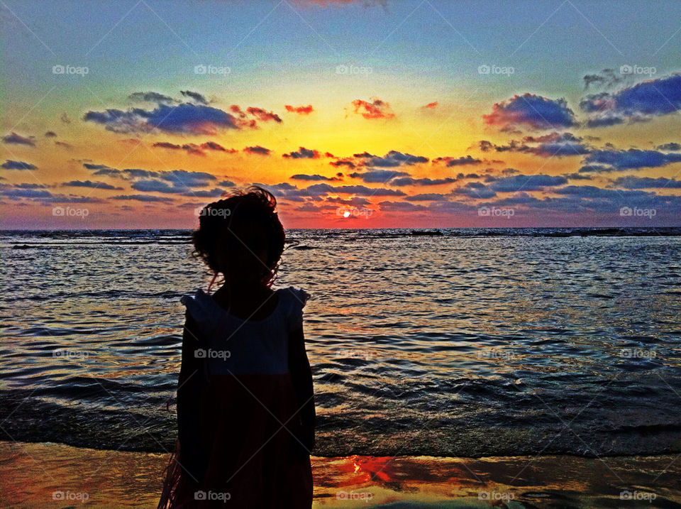 Little girl on the sunset background