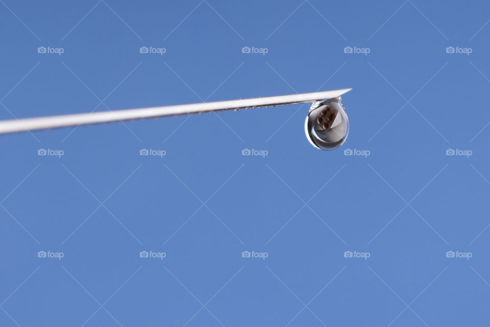 Close-up or macro of syringe needle with a drop at the tip on a blue background .
reflection of pills in a drop. Hospital, health, care, doctor, injection, vaccine, vaccination, illness, disease