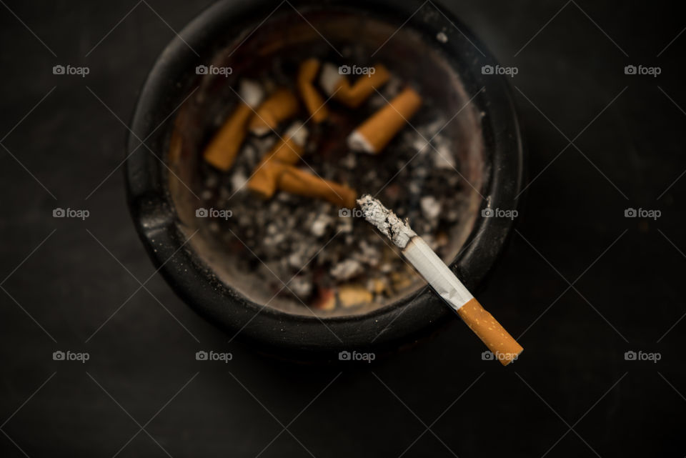 ashtray and smoldering cigarette - unhealthy addiction