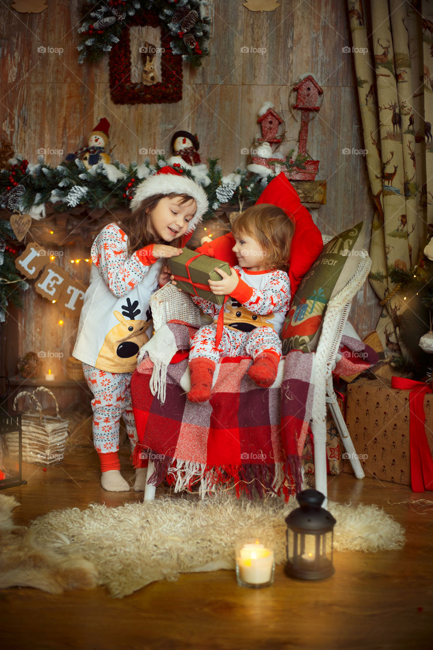 Little sisters near fireplace at Christmas Eve 