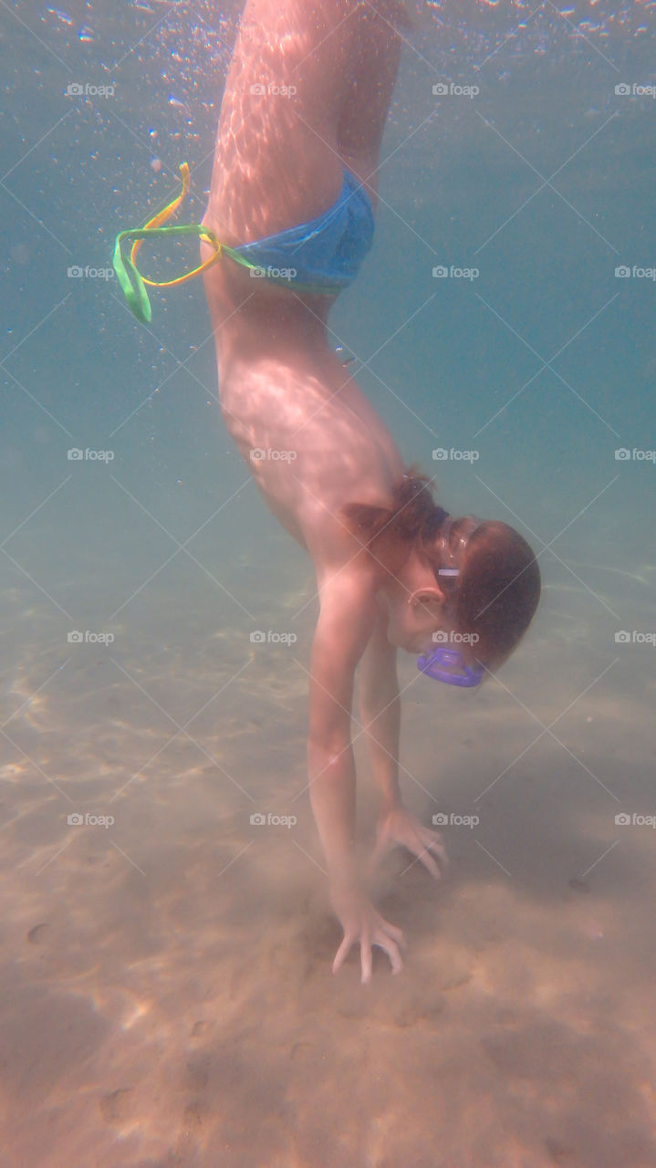 young girl dive underwater, making stay on her hands