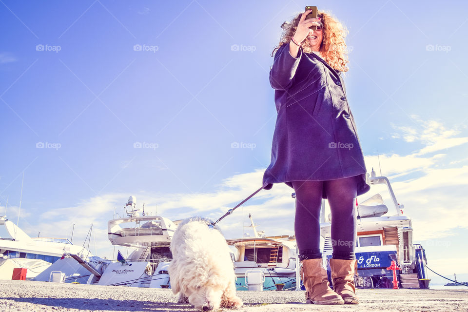 Young Woman With Her Dog Using Mobile Phone Outside