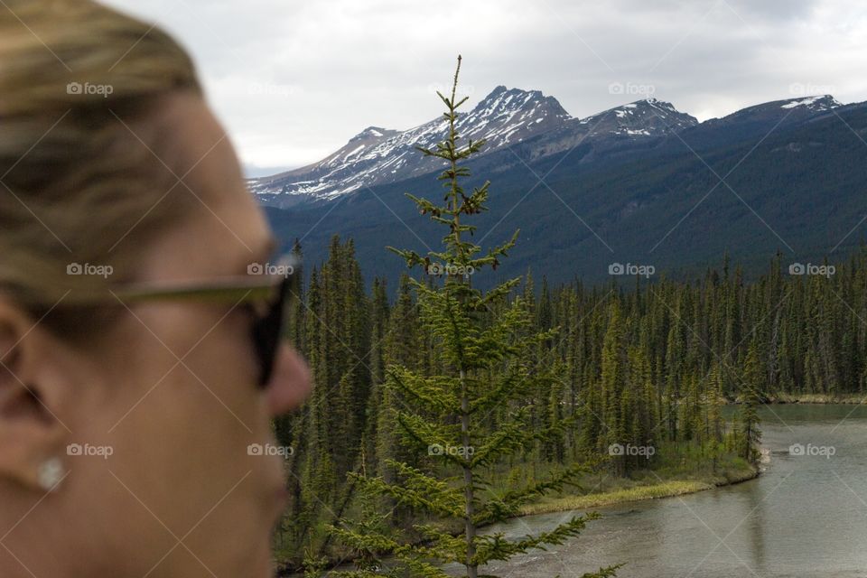 Woman in foreground blurred wearing sunglasses taking in the view of Canada's Rocky Mountains 