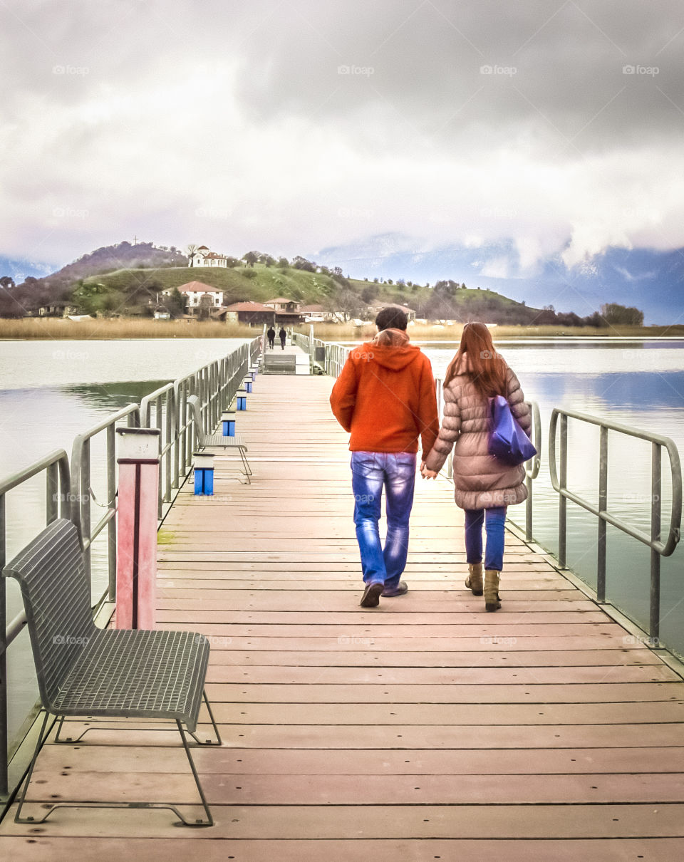 Young Couple In Love Walking Across A Bridge Holding Hands
