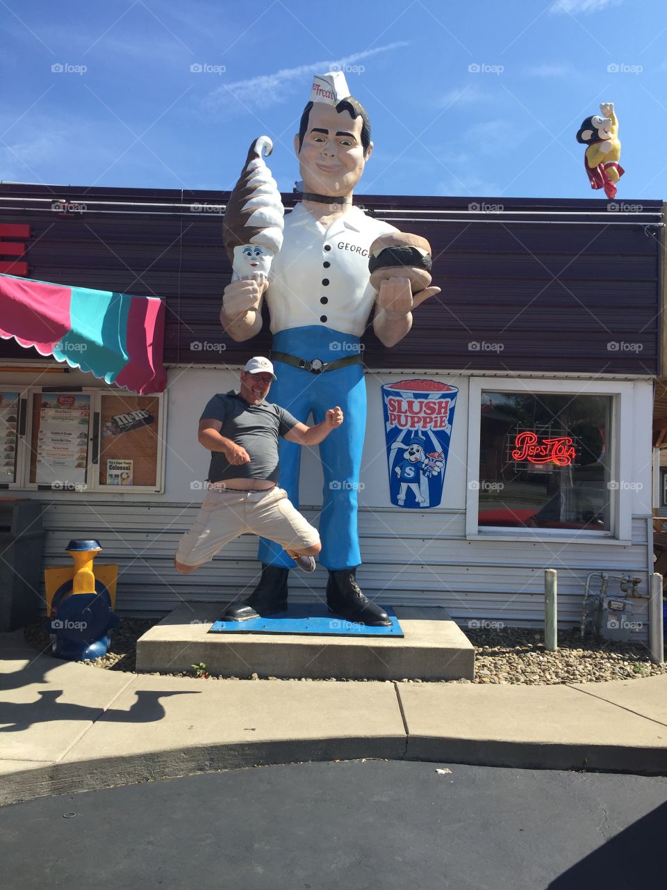 Man jumping in front of large roadside giant statue at fast food restaurant- funny