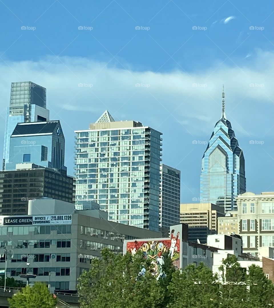 A city skyline against a blue sky with white clouds in the daytime 