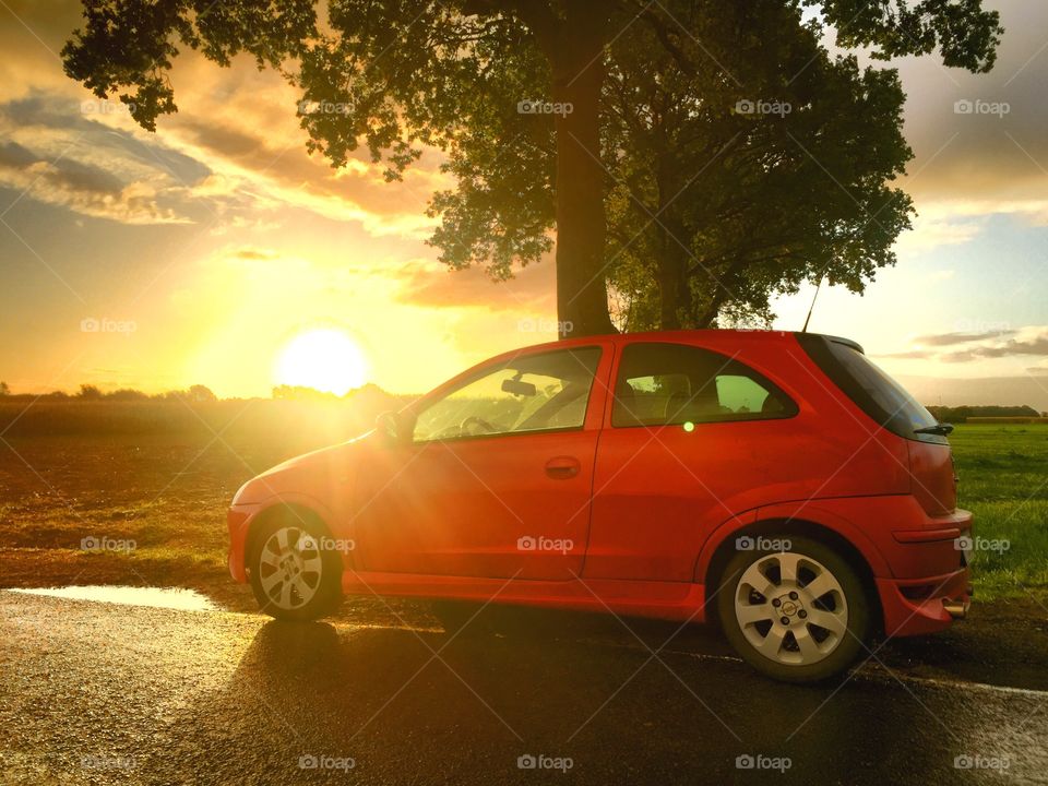 Small red car in a sunrise landscape