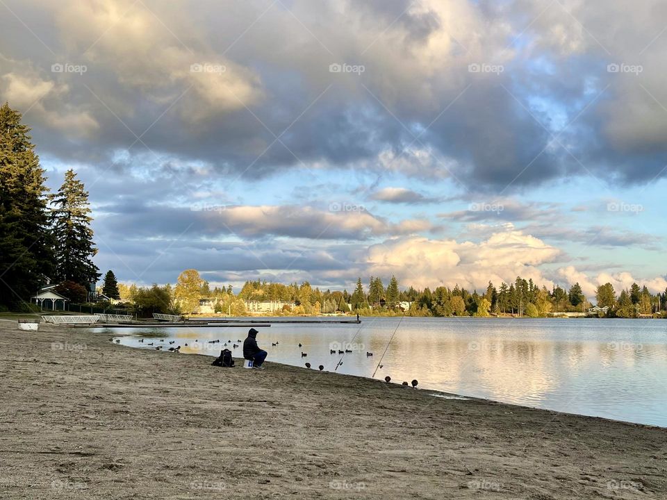 Evening landscape on the lake with fish man