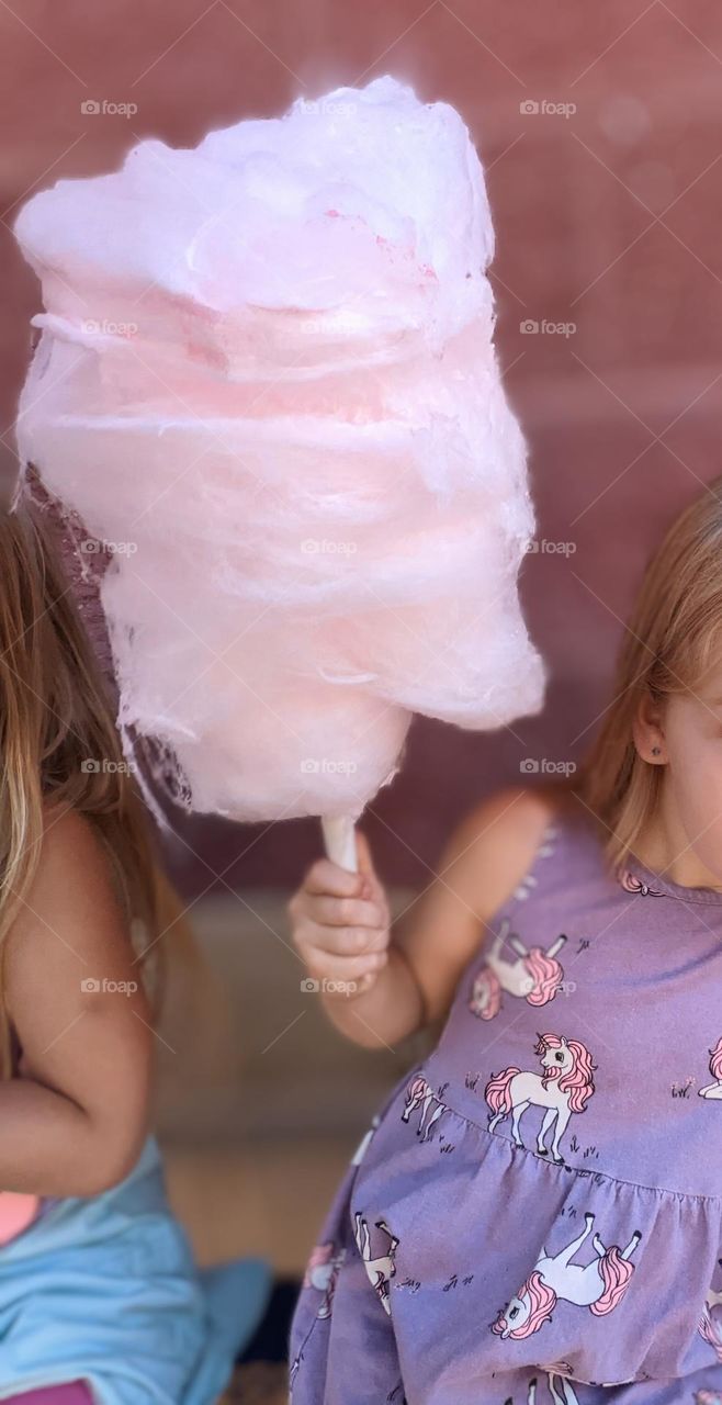 soft pink cotton candy in front of a purple pink brick wall and girl wearing a purple summer dress, barbie style