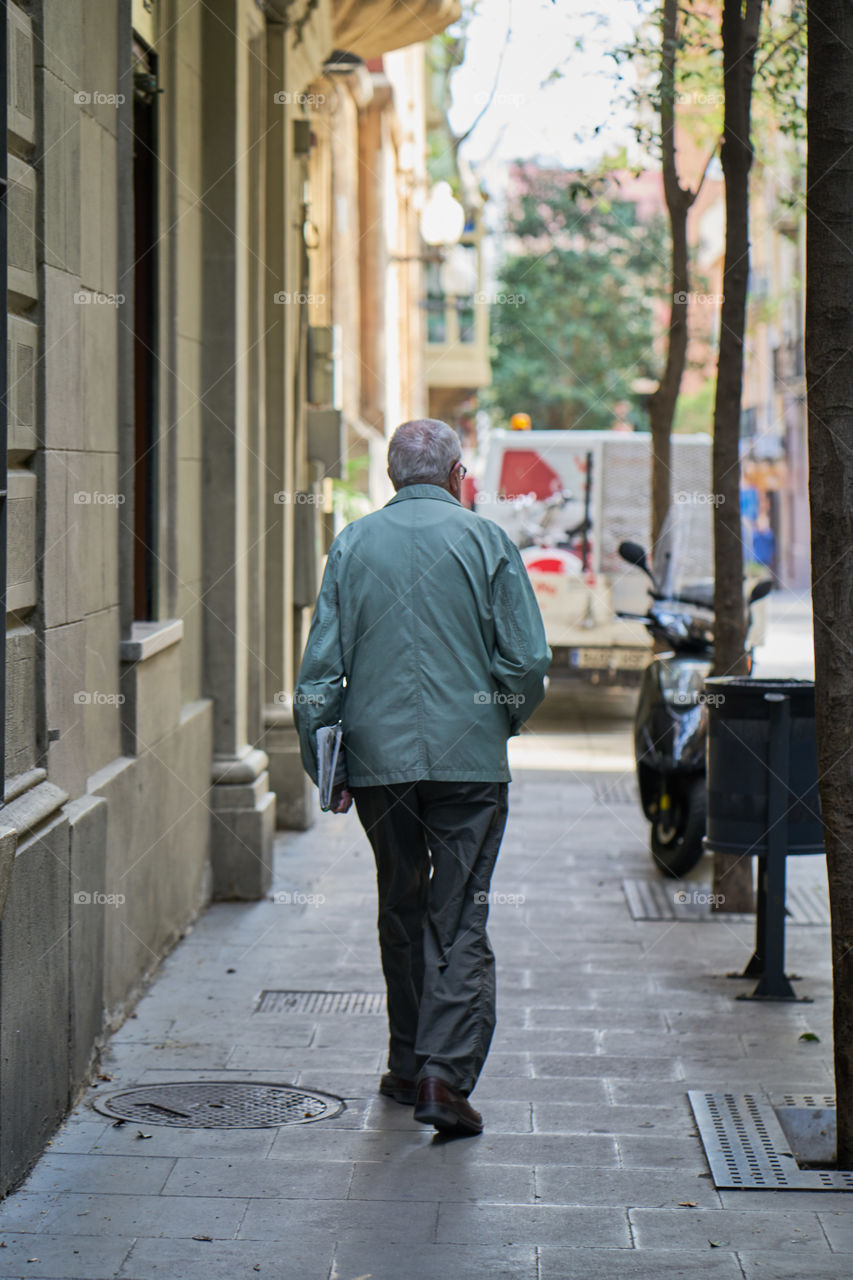 Elderly man  with a newspaper walking