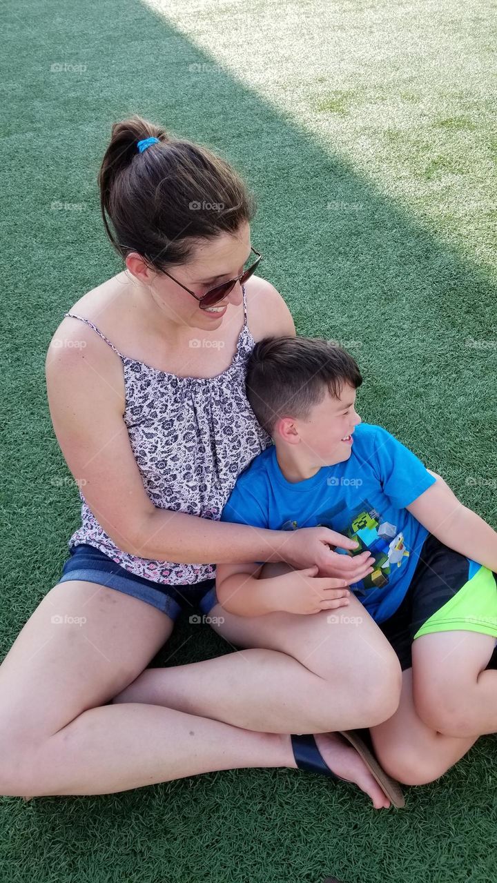 Mom and son having a bonding moment while waiting outdoors.