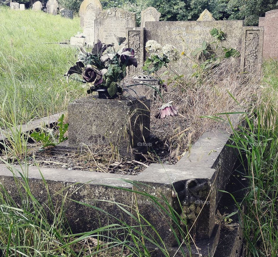 dying flowers on old overgrown Victorian grave