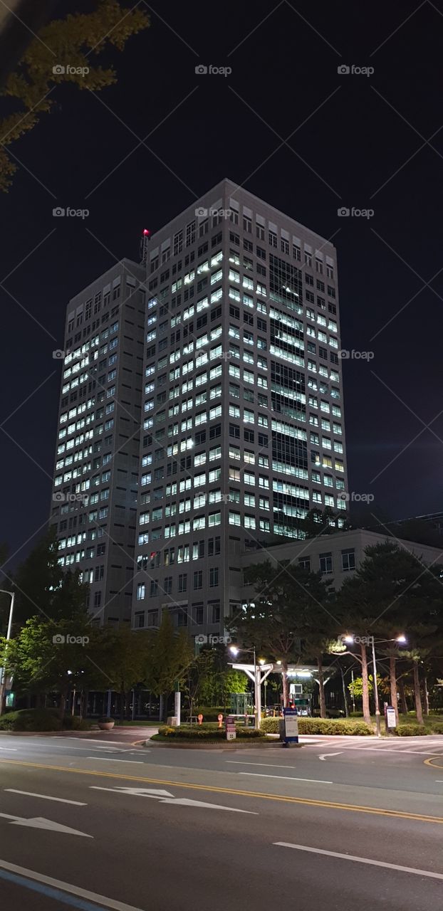 Korea skyscraper at night with lights in windows with street and bus stop