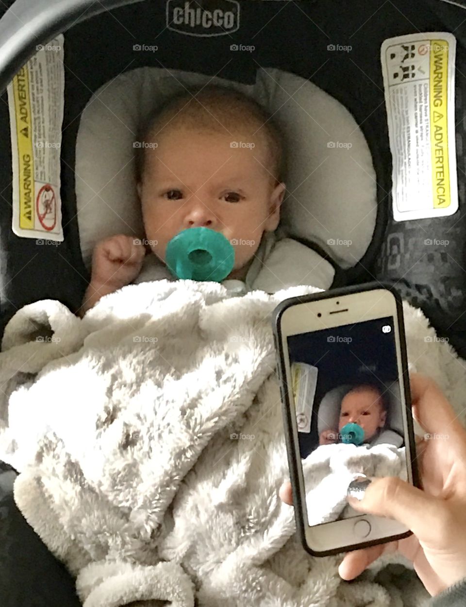 Person's hand taking picture of baby on mobile phone