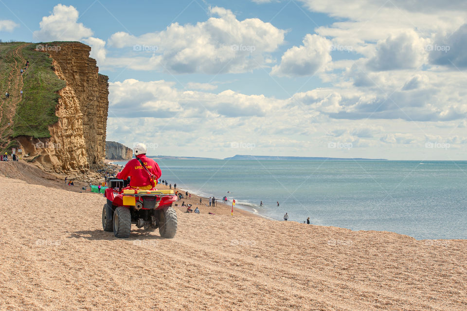 Lifeguard on quad patrolling beach.