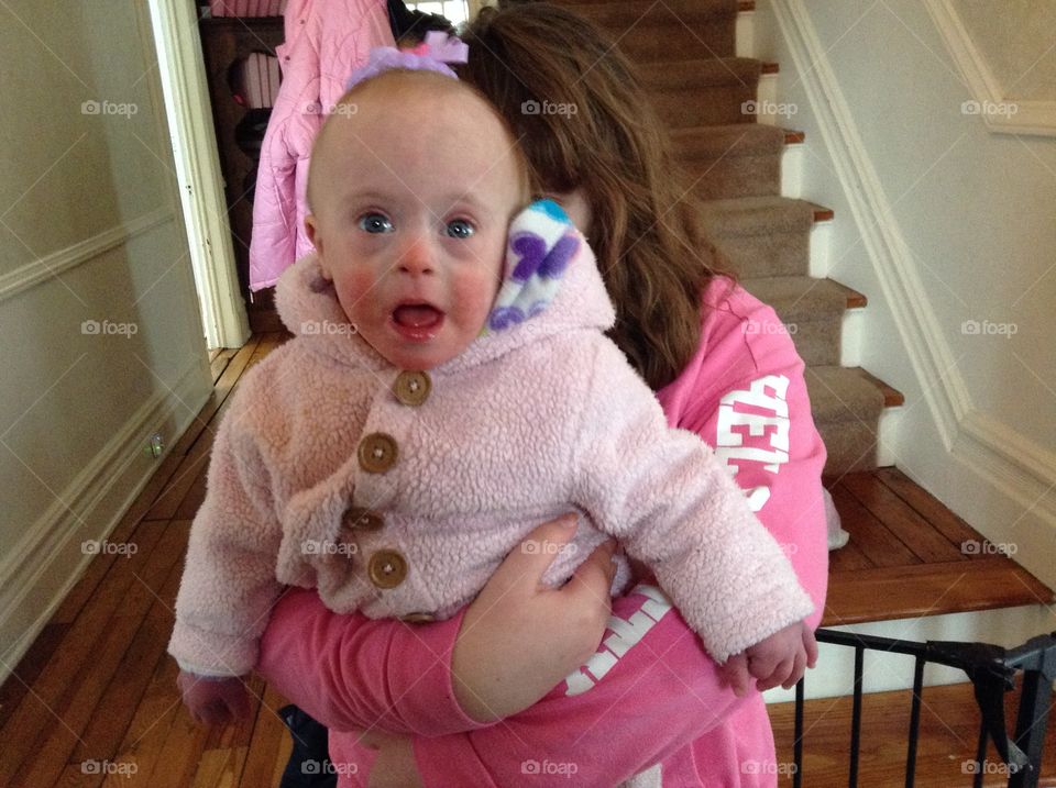 Baby with Down syndrome being held by her sister