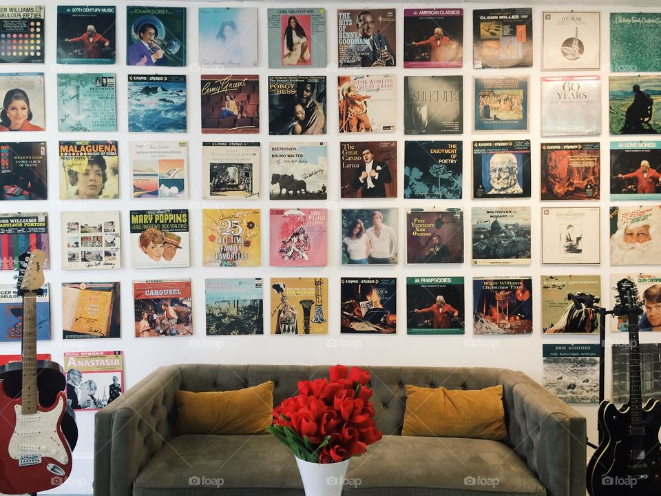 Retro vinyl albums hung symmetrically on a wall, a cozy couch, and a vase of flowers