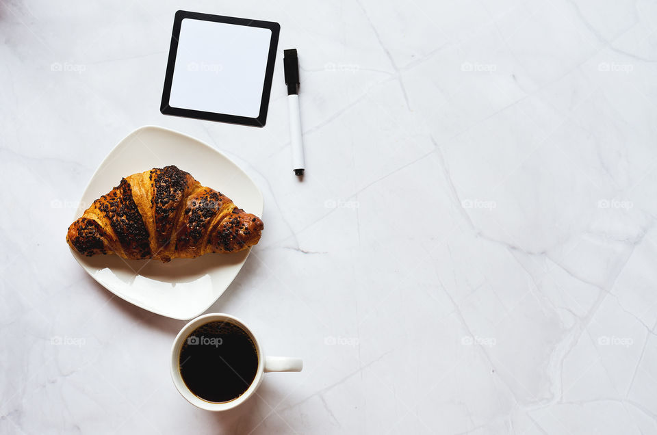 Business working morning with cup of hot coffee, sweet croissants, pen, notebook on white background close up. Top view, copy space, flat lay, mockup.