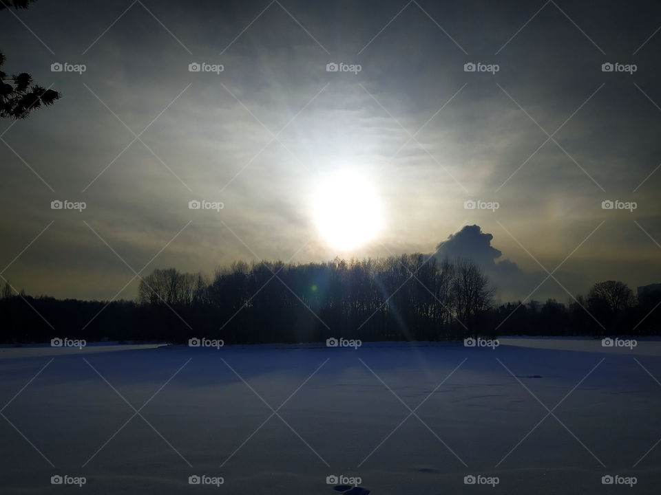 Dawn over a snowy forest and a frozen body of water in Moscow