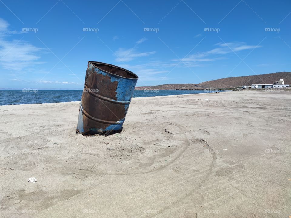 A drum that serves as a trash can on a beach