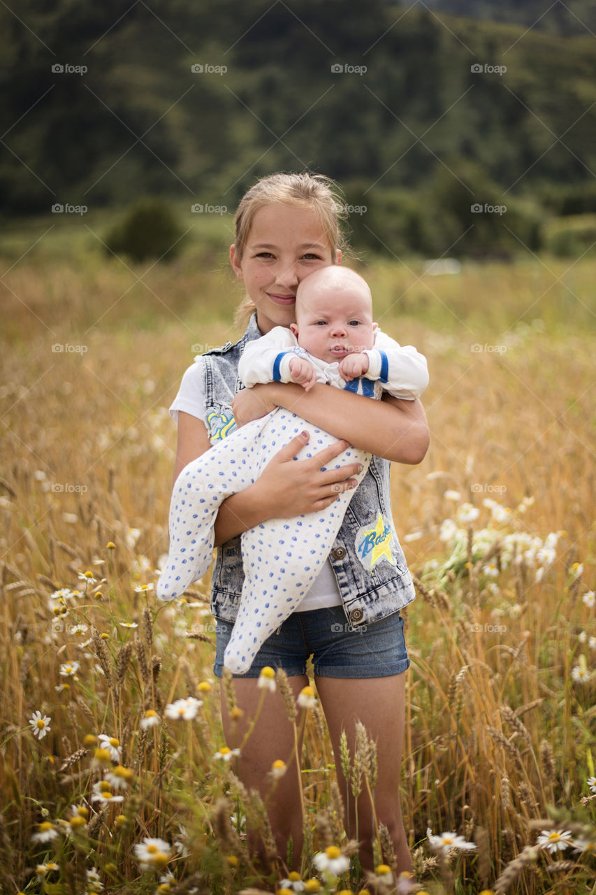 Sister carrying baby in hand