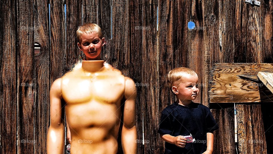 A little boy standing behind headless mannequin