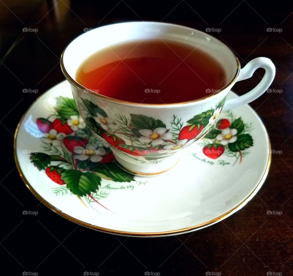 strawberry teacup and saucer with tea