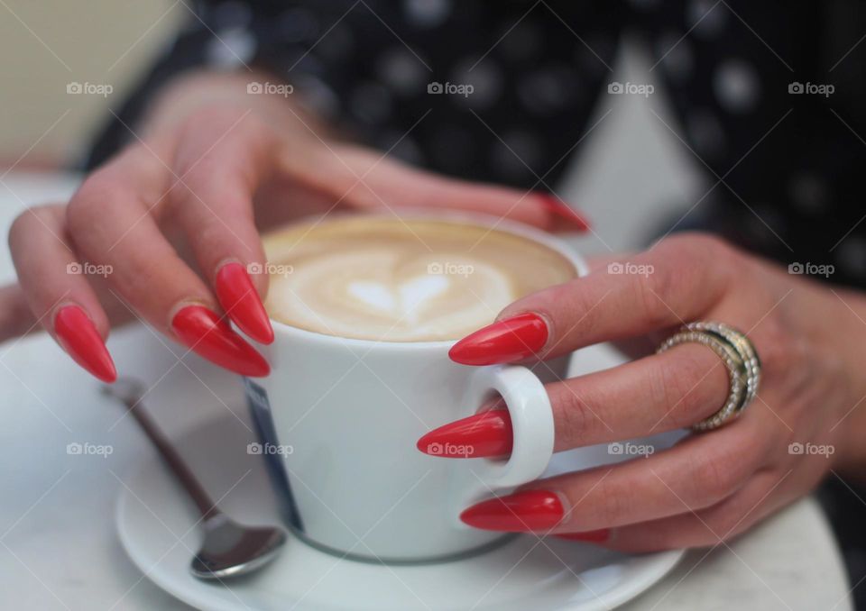 Woman hands red long nails with cappuccino cup