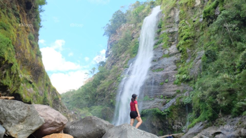 Hiker looking up at a waterfalls