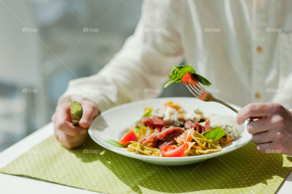 close-up of a young man eating a salad in a light kitchen