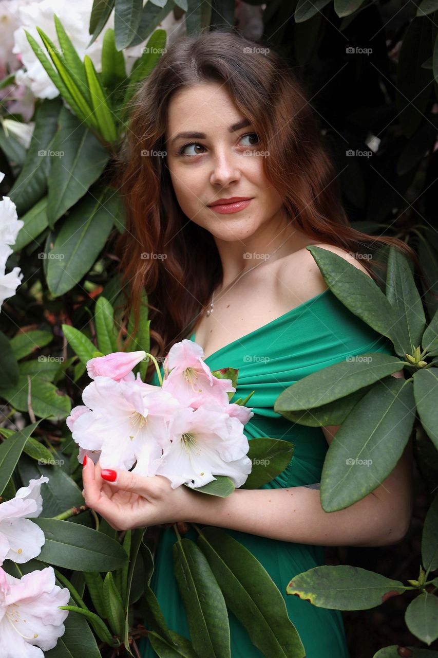 Natural womаn, natural beauty. Young women with long hair. Woman portrait with pink flowers in the green garden. Without any digital retouching. Elegant lady with nice smile. Spring time, blooming time.