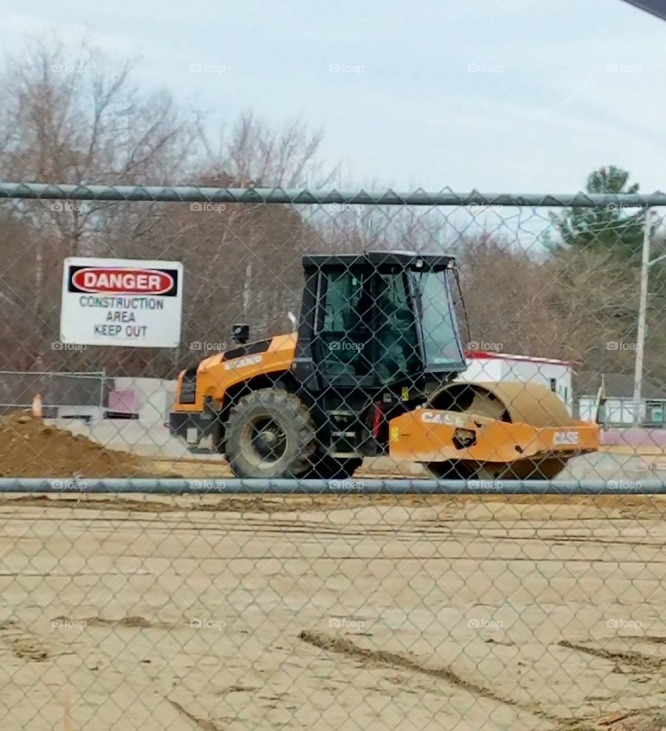 Heavy construction equipment on job site, moving gravel & rocks. Loud & fast moving, small but strong piece of machinery in bright yellow.